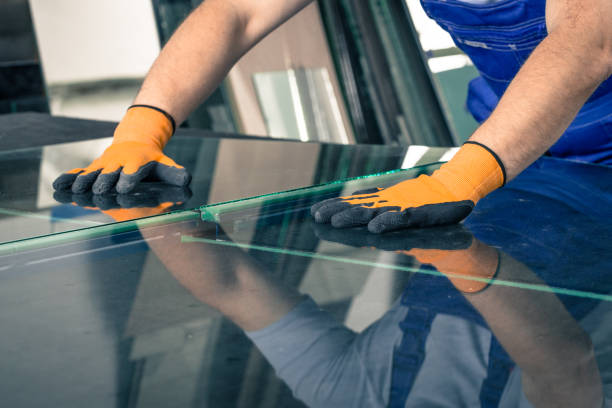 A worker cuts and breaks glass on a professional table in a workplace